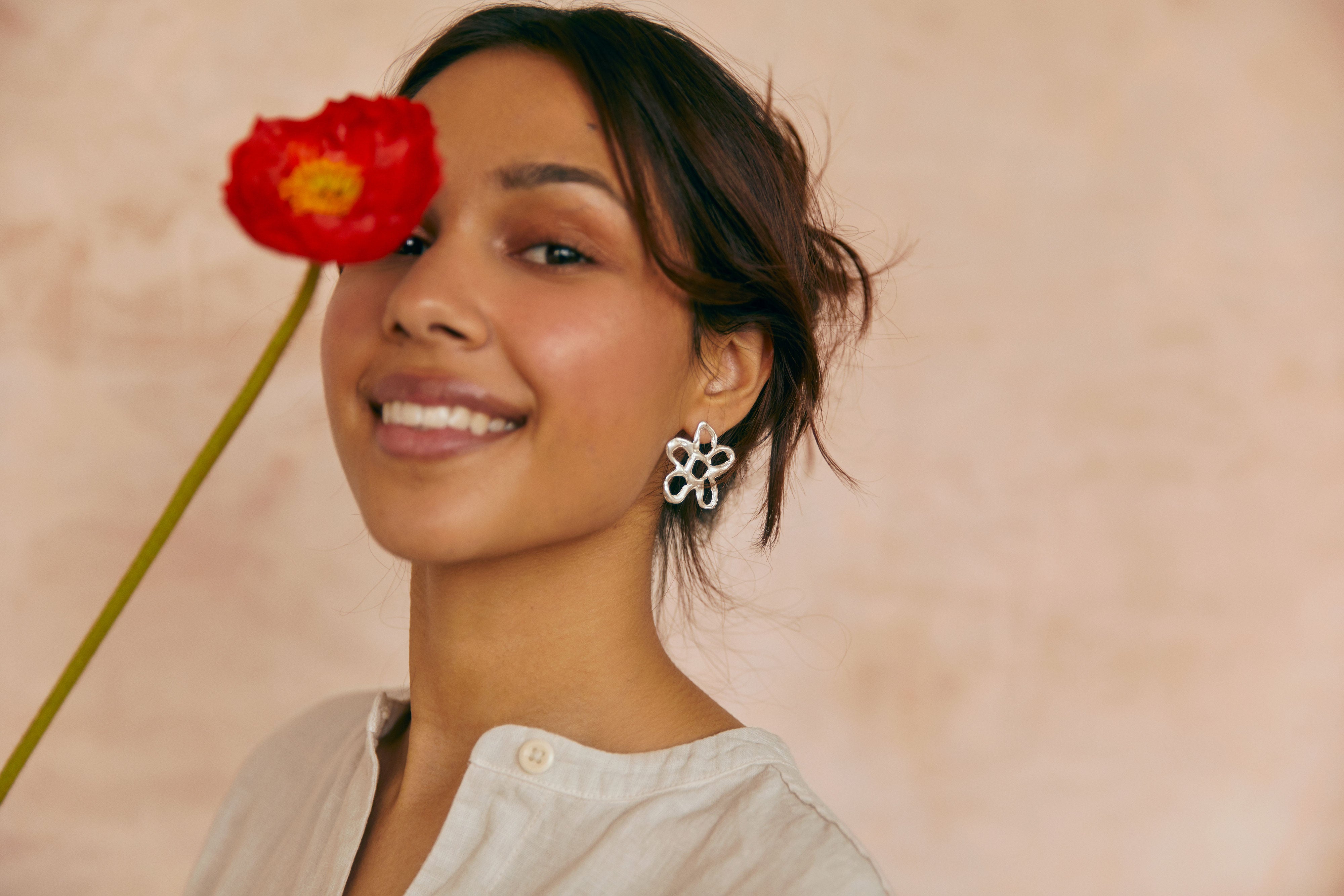 blossom statement studs worn by model holding red poppy