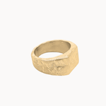A textured, chunky signet-style ring in a warm gold finish, photographed on a clean, solid off-white background.