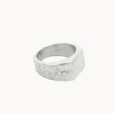 A textured silver square signet ring with a wide, chunky band and a hammered, organic surface finish, shown on a plain off-white background.