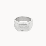 A textured silver square signet ring with a chunky, organic, faceted band, shown against a plain off-white background.