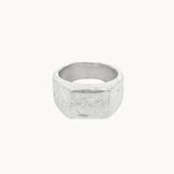A textured silver square signet ring with a chunky, organic, faceted band, shown against a plain off-white background.