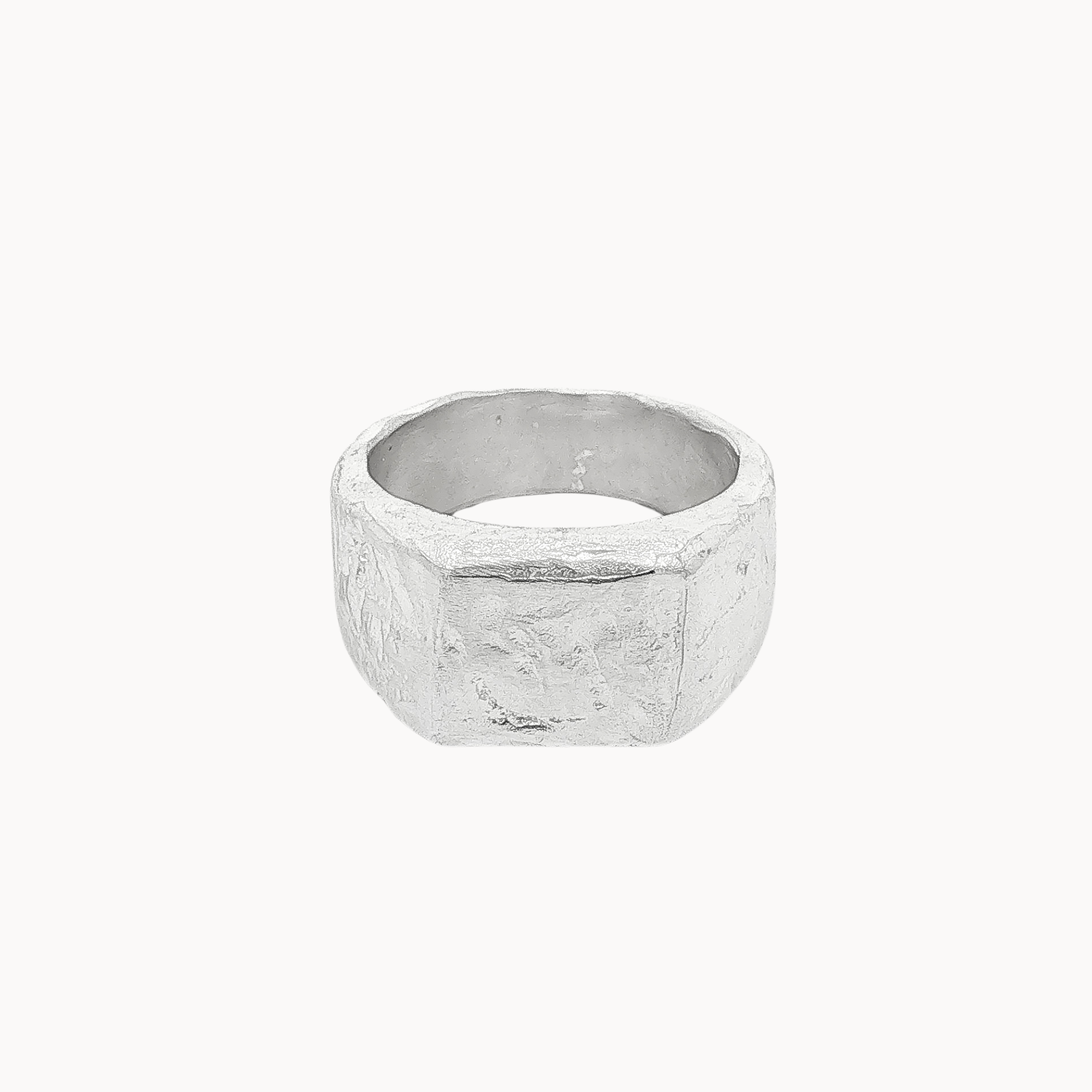 A textured silver square signet ring with a chunky, organic, faceted band, shown against a plain off-white background.