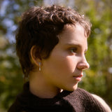 Woman wearing silver star dangle earrings and dark brown scarf with a blurred natural background