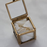 gold ring with tar and diamonds in glass ring box with ribbon