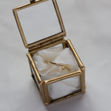 gold ring with tar and diamonds in glass ring box with ribbon