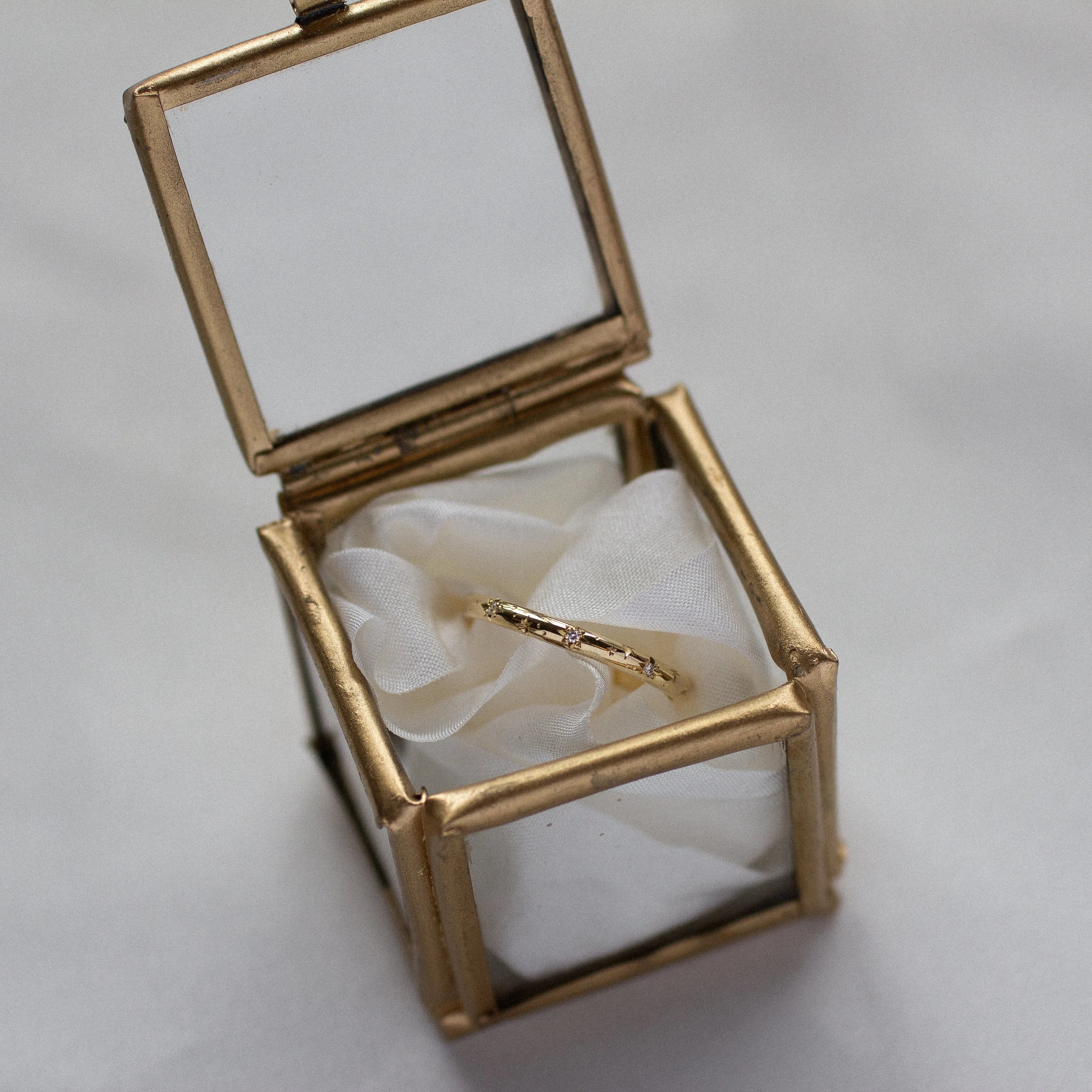 gold ring with tar and diamonds in glass ring box with ribbon