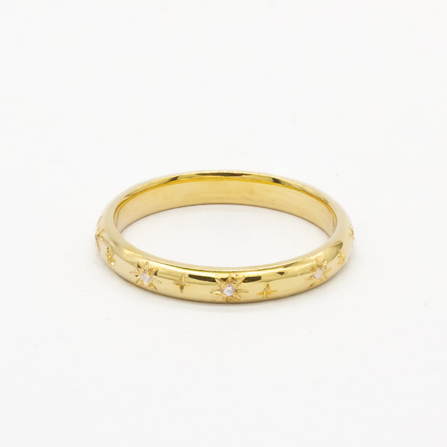 Gold 2mm thick wedding ring with small diamonds and star engraving on a white background