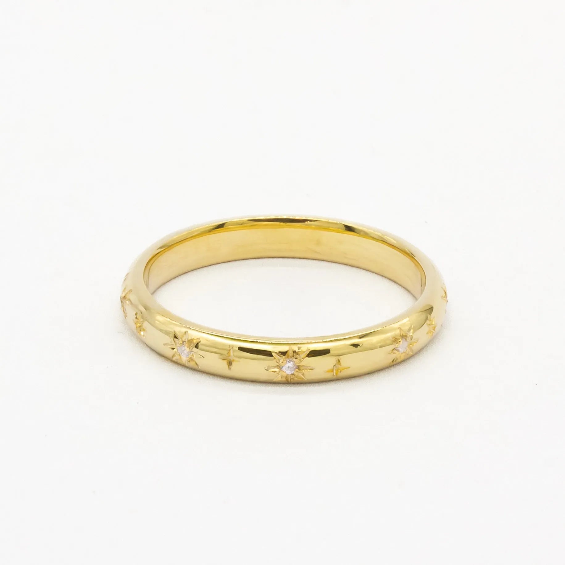 Gold 2mm thick wedding ring with small diamonds and star engraving on a white background
