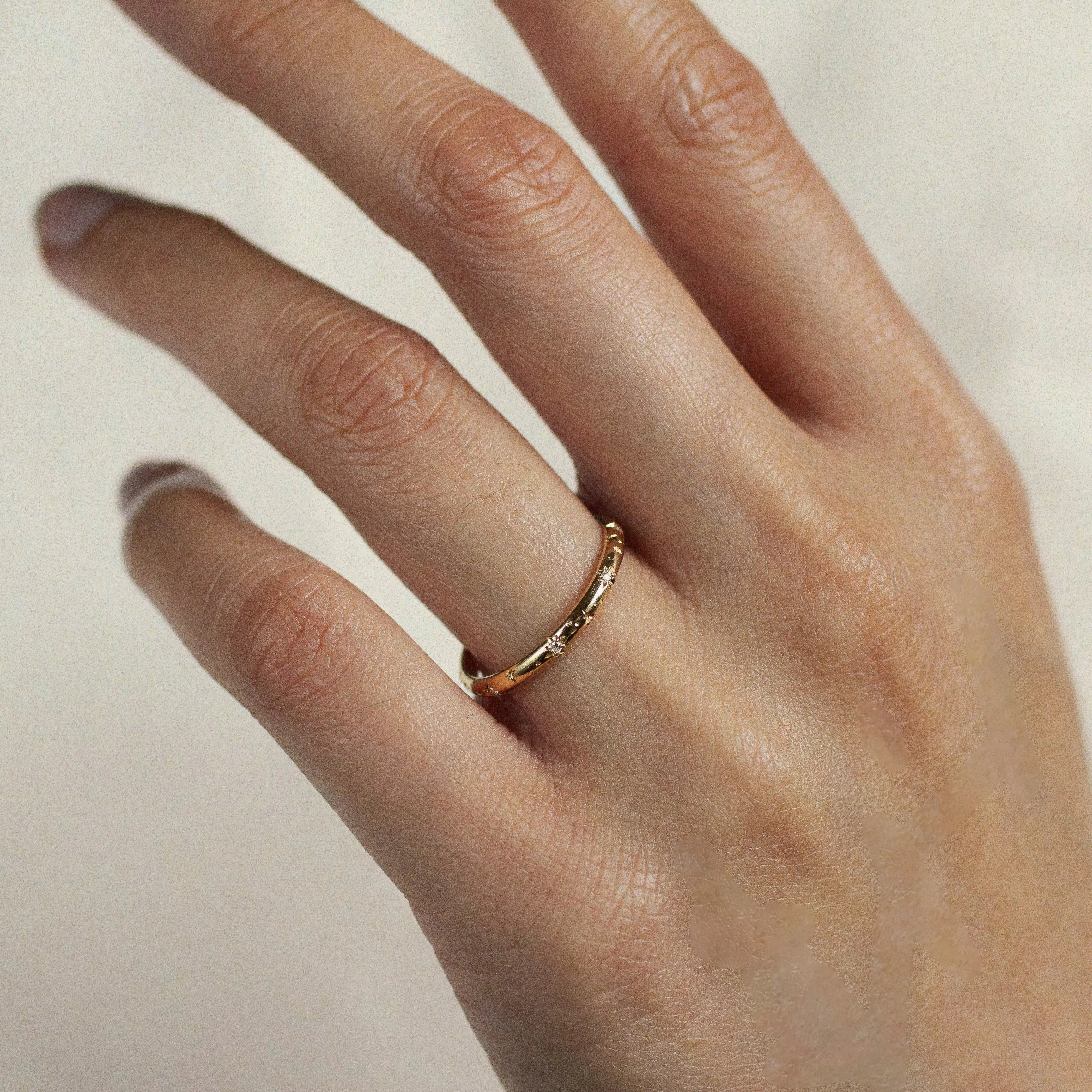 close up of hand wearing gold wedding ring with small diamonds and star engraving