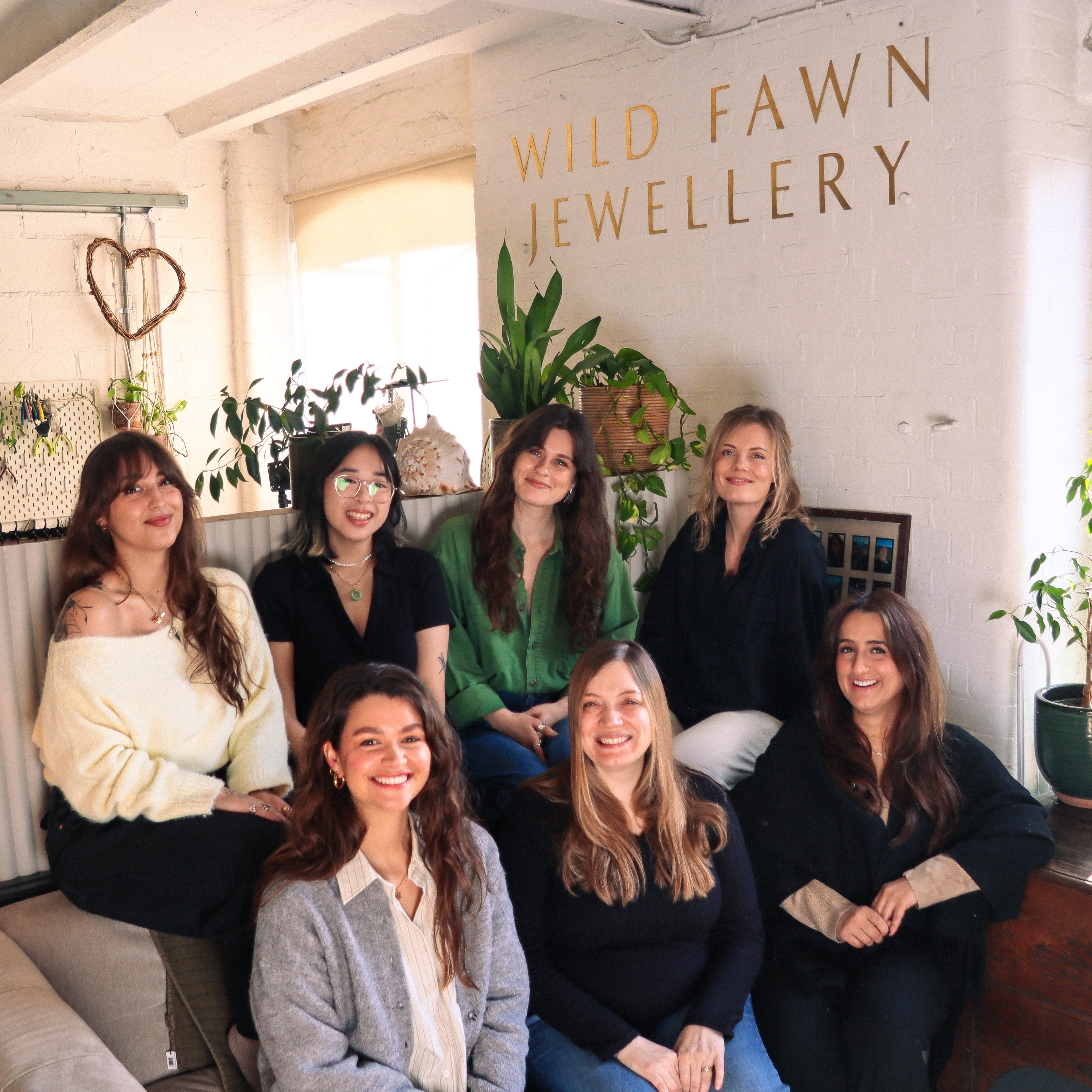 Group of women posing together in a room with 'Wild Fawn Jewellery' branding.