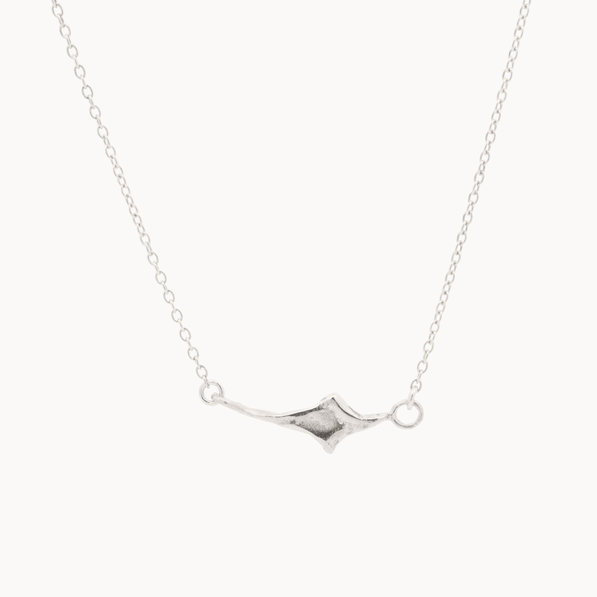 white gold four point star necklace on a fine chain against a white background