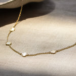 gold chain necklace with tiny sun shaped pendants on a fabric surface