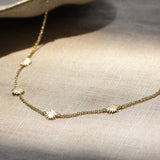 gold chain necklace with tiny sun shaped pendants on a fabric surface