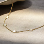 gold chain necklace with tiny sun shaped pendants on a fabric surface