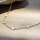 gold chain necklace with tiny sun shaped pendants on a fabric surface