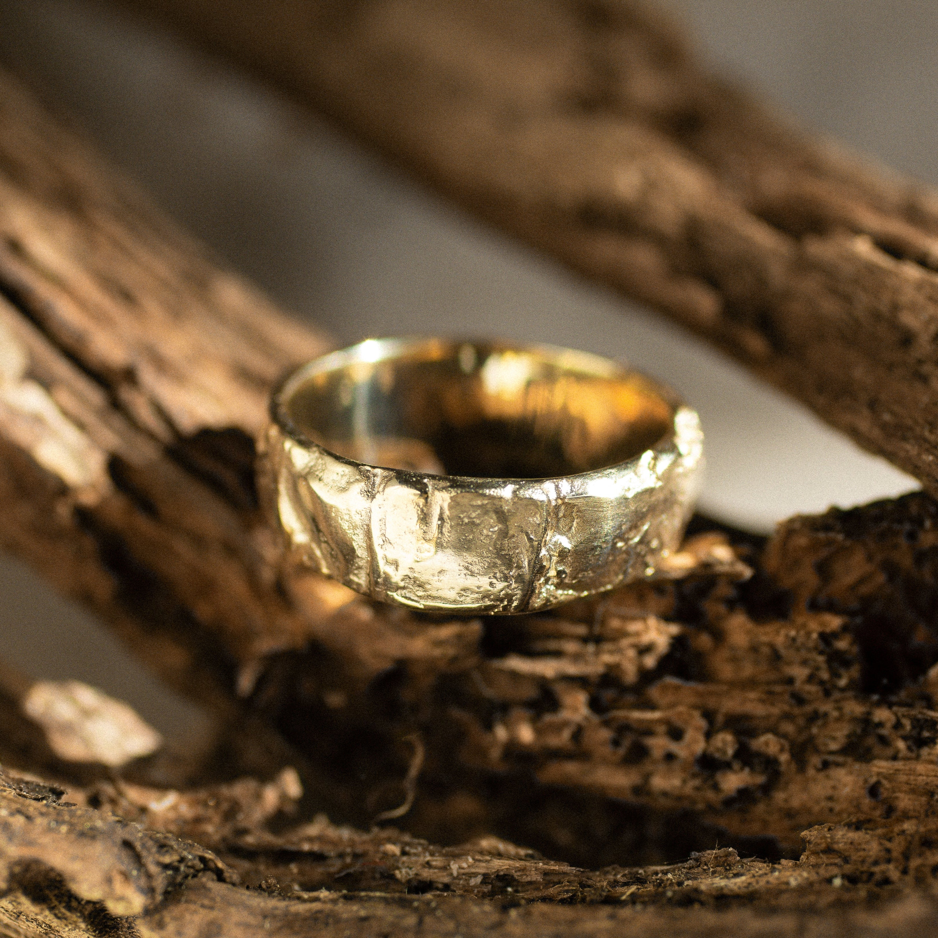 Gold ring with tree bark texture on a rustic wooden background