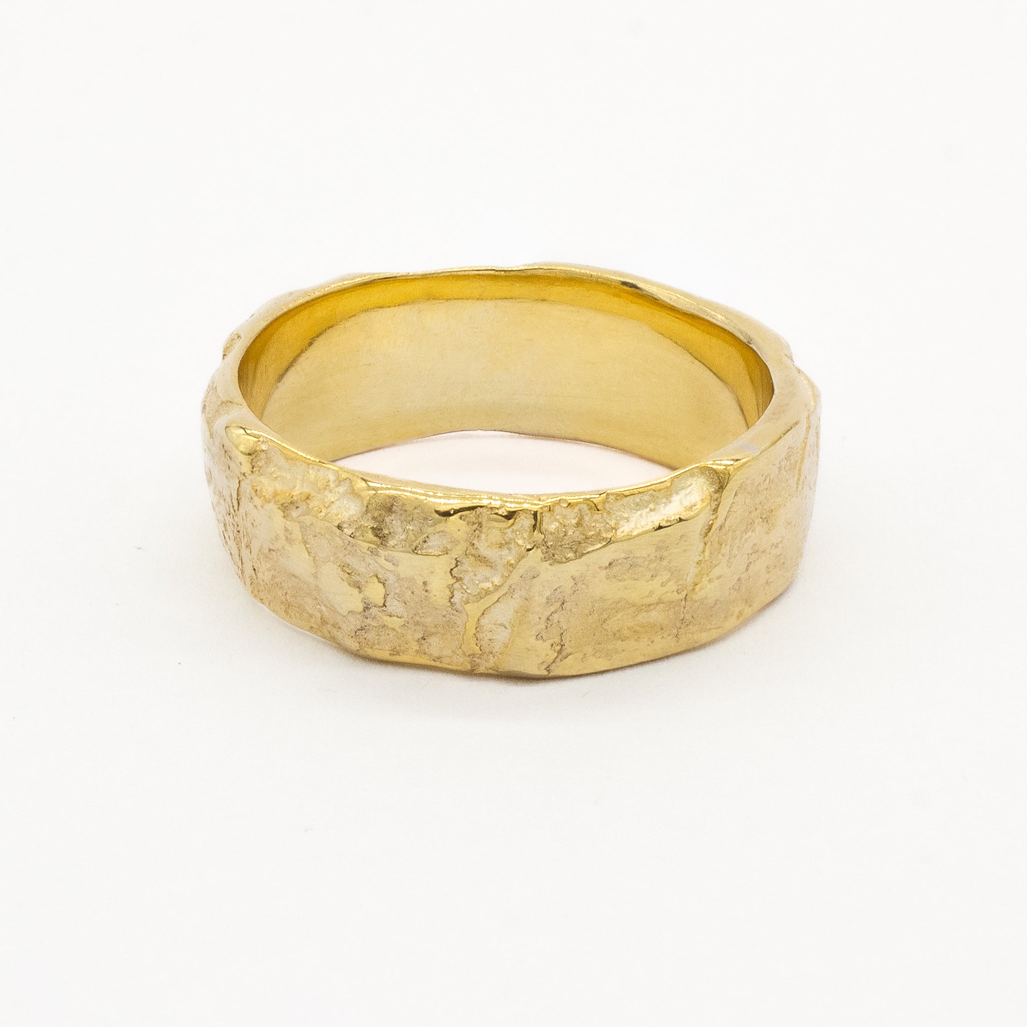 Gold wedding ring with a textured tree bark surface on a white background