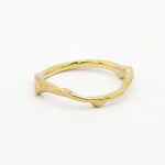 Gold wedding ring with a unique tree branch design on a white background