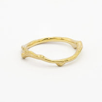 Gold wedding ring with a unique tree branch design on a white background