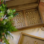 Wooden jewelry box with gold rings on a wooden surface with flowers.