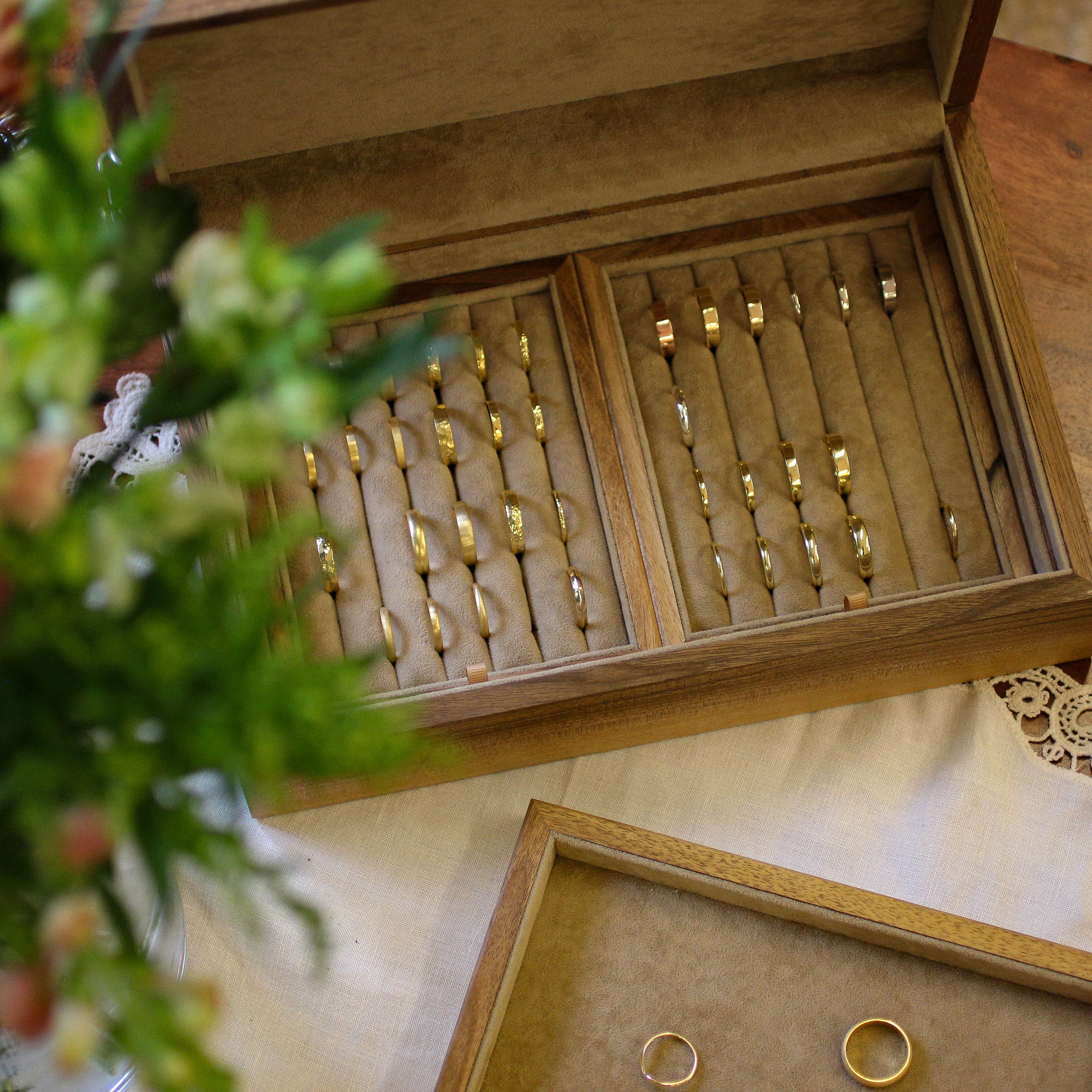 Wooden jewelry box with gold rings on a wooden surface with flowers.