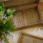 Wooden jewelry box with gold rings on a wooden surface with flowers.