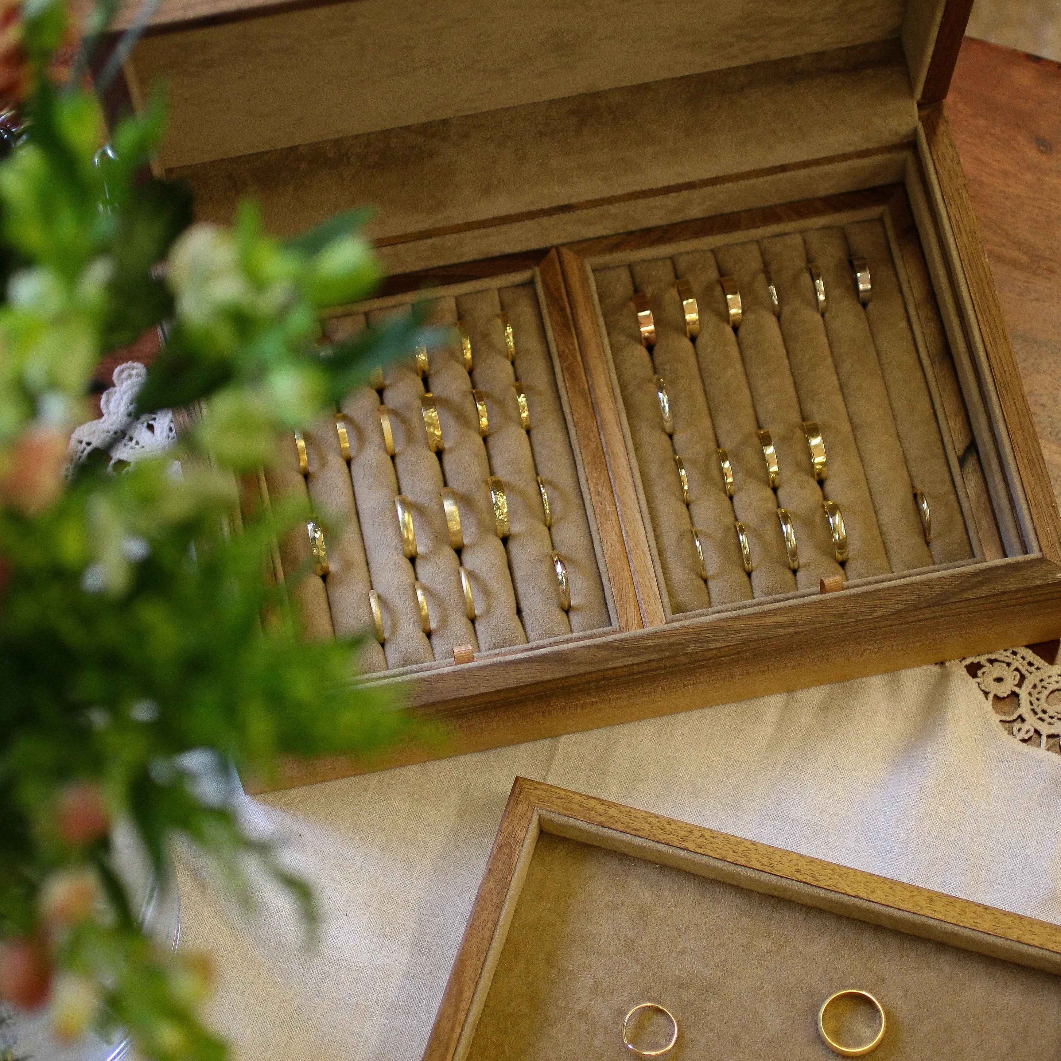 Wooden jewelry box with gold rings on a wooden surface with flowers.