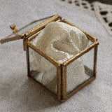 glass ring box with ribbon on a neutral fabric