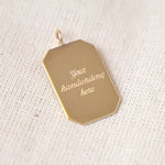 Gold pendant with 'Your handwriting here' text on a textured beige background